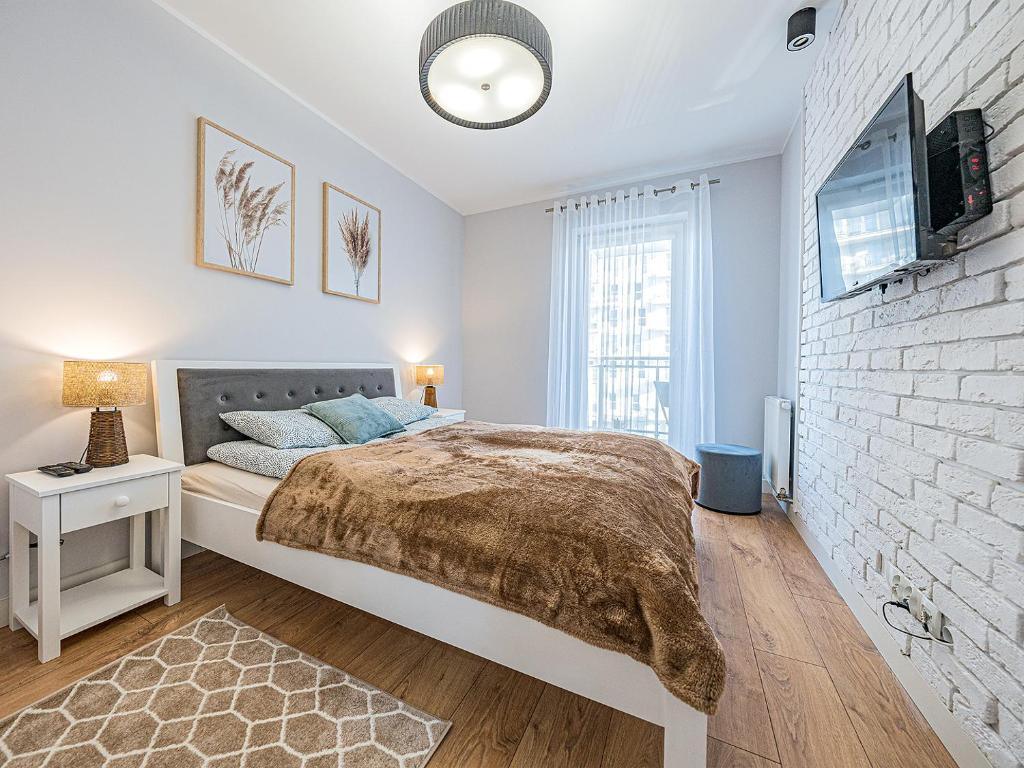 a bedroom with a bed and a brick wall at Hello Apartments 4 Oceany z prywatnym parkingiem in Gdańsk