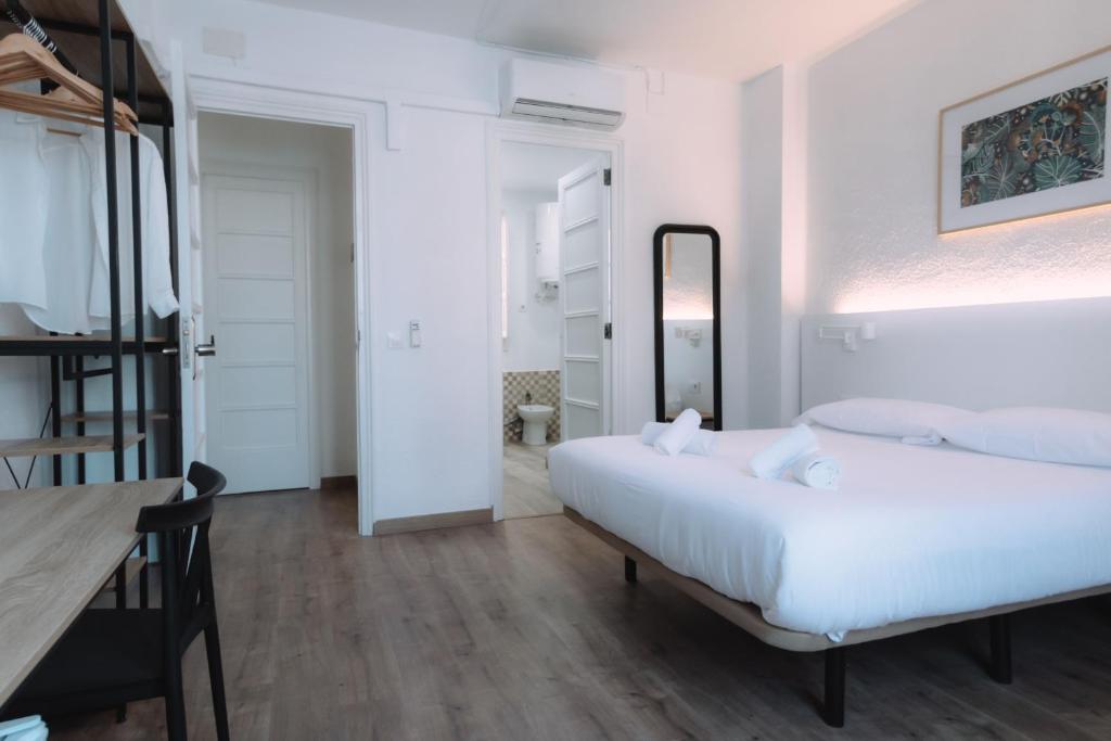 a white bedroom with a bed and a table at Clink Rooms & Flats in Valencia
