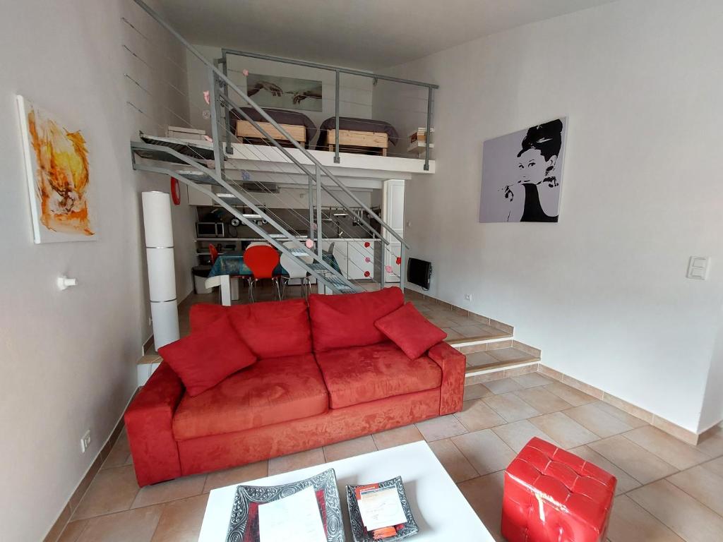 Gite Europa في Le Mas: غرفة معيشة مع أريكة حمراء وطاولة