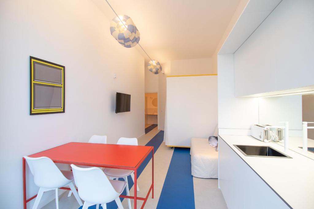 cocina y comedor con mesa roja y sillas blancas en Marino by Concept, en Valencia