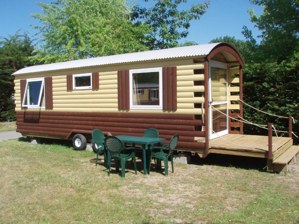 a tiny house with a table and chairs in the yard at Camping La Mignardière in Ballan-Miré