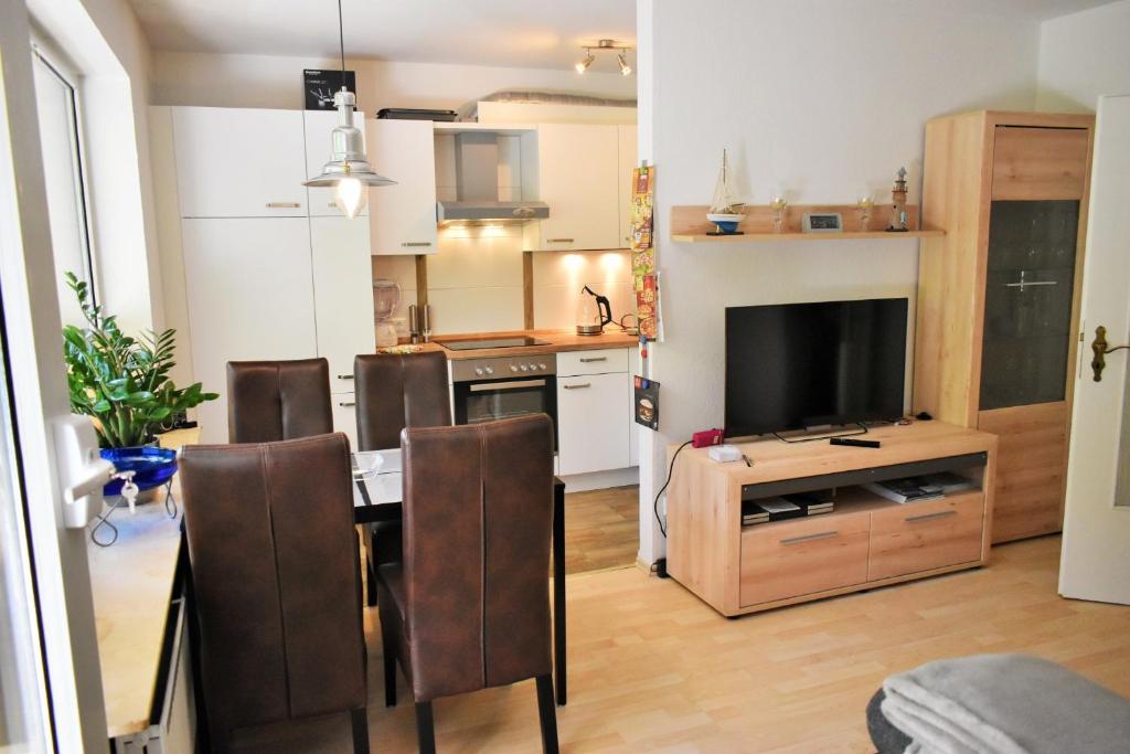 a living room with a kitchen with a table and a television at Möwennest am Twedter Holz in Flensburg
