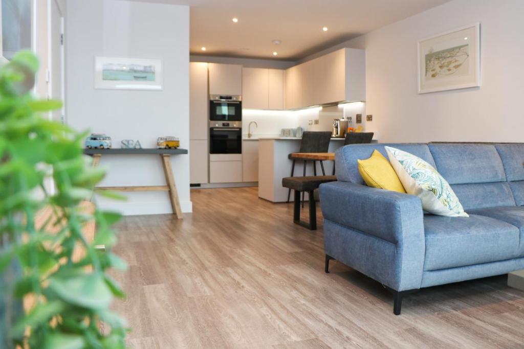 a living room with a blue couch and a kitchen at Sea view apartment, first floor in Saint Merryn