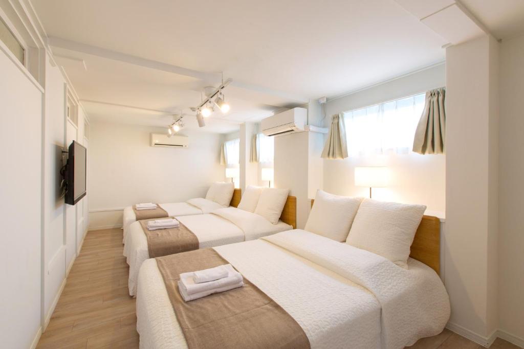 大阪市にあるHaginochaya apartmentの白い壁と窓が備わる客室で、ベッド2台が備わります。