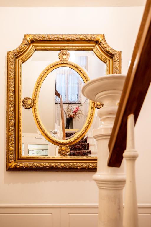 a gold mirror on a wall next to a staircase at Hotel Restaurant Café Parkzicht in Roermond