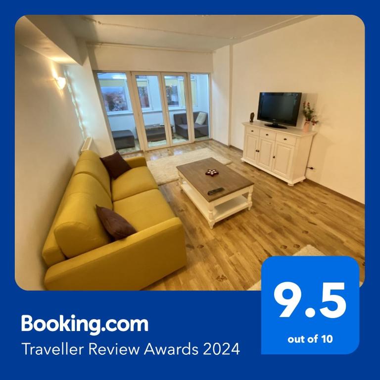 a living room with a yellow couch and a tv at Downtown Apartment in Craiova