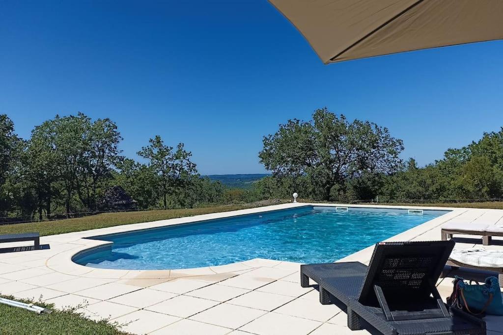 una piscina con 2 sillas y una sombrilla en Les Tavernes*Authentique*Calme*Piscine, en Daglan