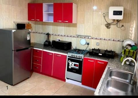 eine Küche mit roten Schränken, einem Herd und einer Spüle in der Unterkunft Specfield Court And Apartment Sun City 