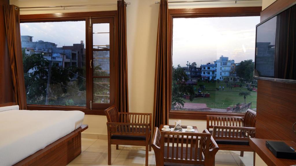 a bedroom with a bed and two chairs and a large window at Hotel Park Street in Pathānkot