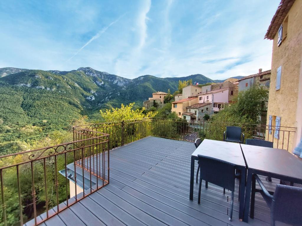 a wooden deck with a table and chairs and mountains at Hellebore in Le Mas