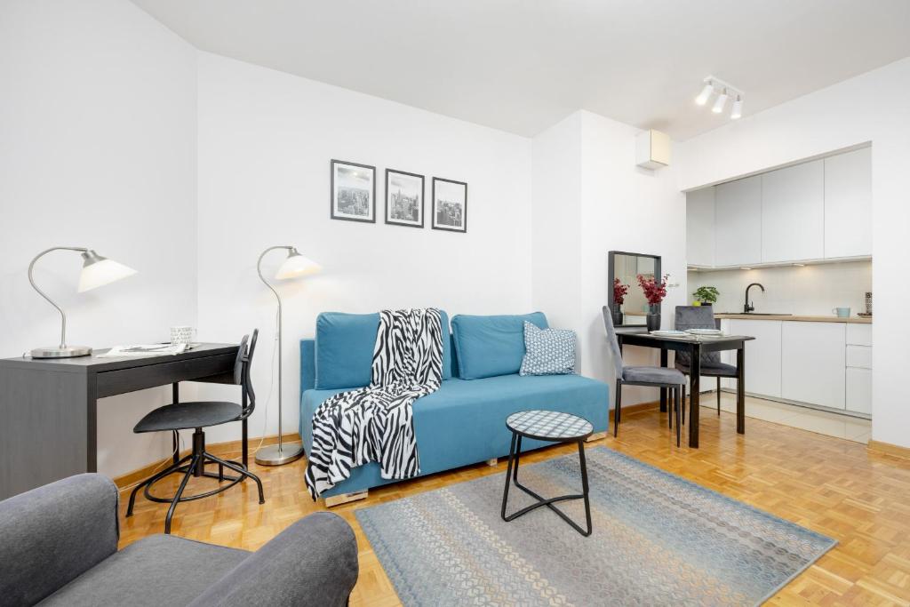 a living room with a blue couch and a kitchen at Bukowińska Apartments with Balcony and Parking and Swimming Pool by Renters in Warsaw