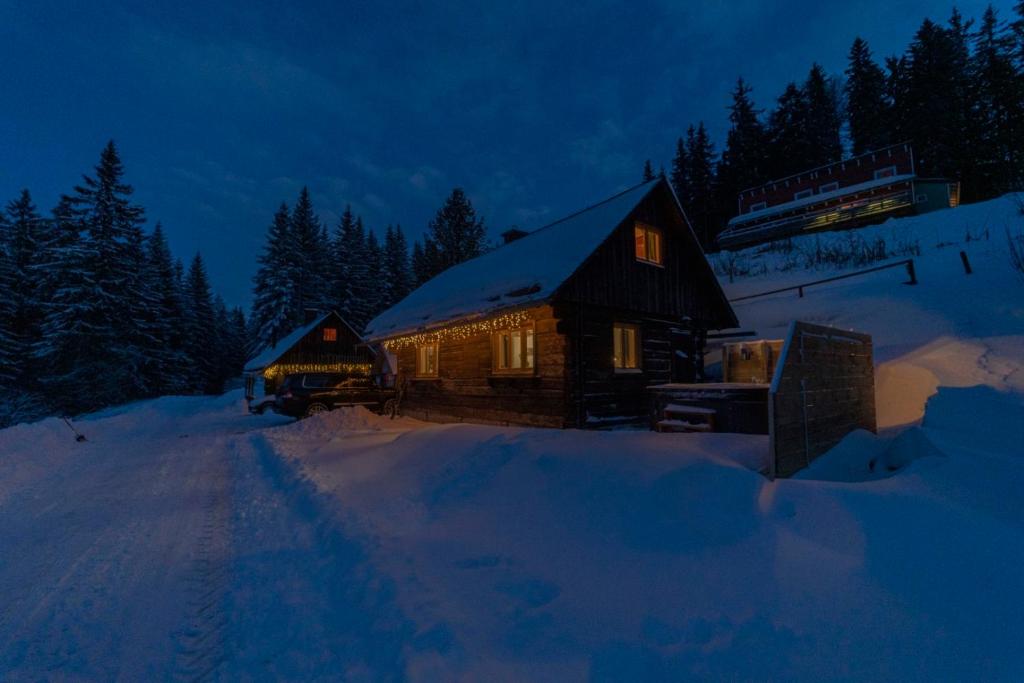 a log cabin in the snow at night at Almhütte Hebalm mit Whirpool in Pack
