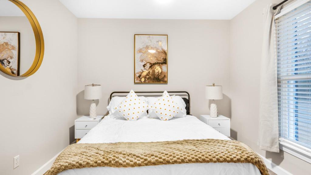 a white bedroom with a bed with pillows and a mirror at 4-bedroom Bliss With Downtown Proximity in Greensboro