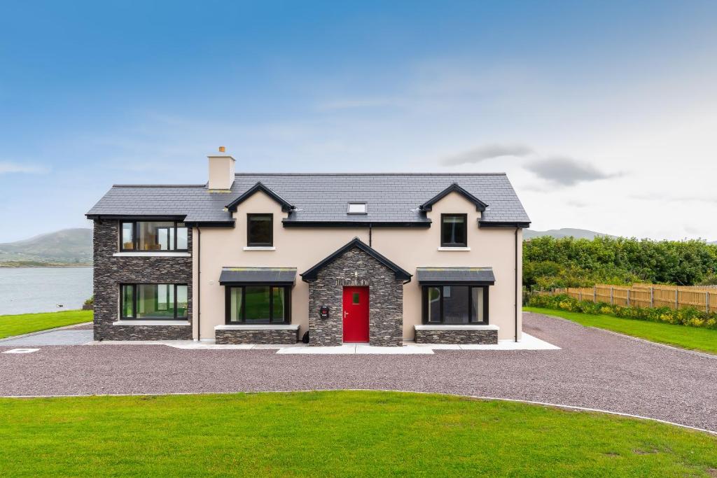 a house with a red door on a driveway at Luxury 4 bedroom holiday home overlooking the sea on Valentia Island in Knights Town