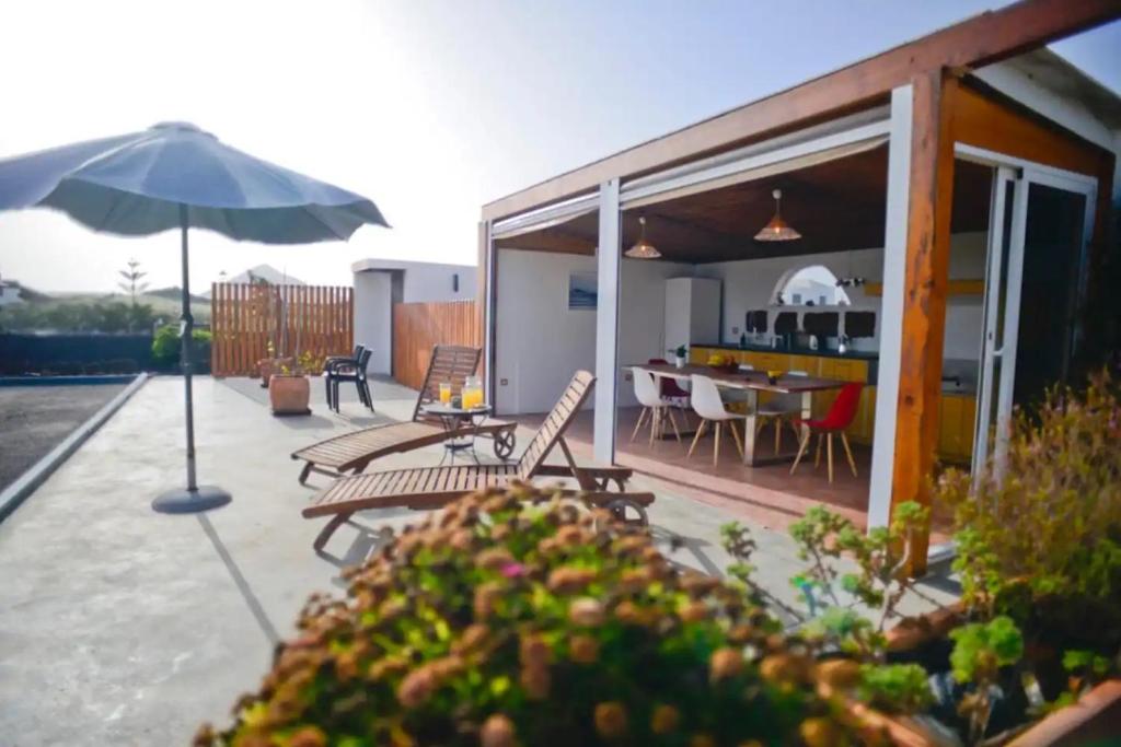 a patio with an umbrella and a table and chairs at Casa Jenabe in La Vegueta