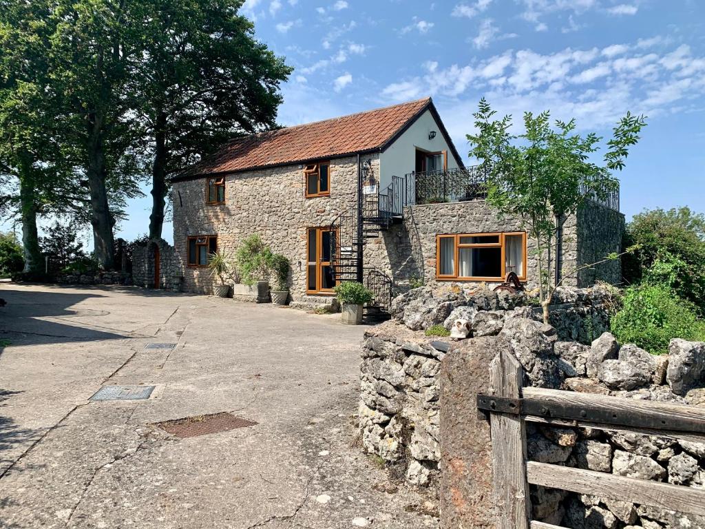 una casa de piedra con una valla delante de ella en Beaconsfield Farm, en Wells