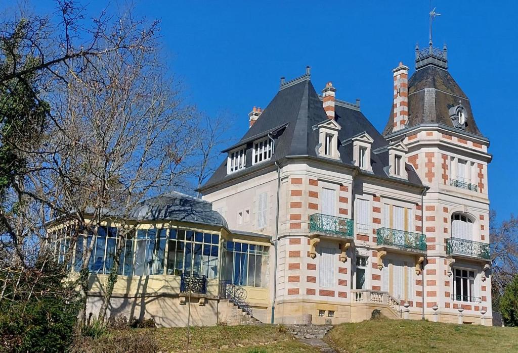Saint-Honoré-les-BainsにあるDomaine des Myosotis, holiday homeの頂上に時計塔がある大きな建物