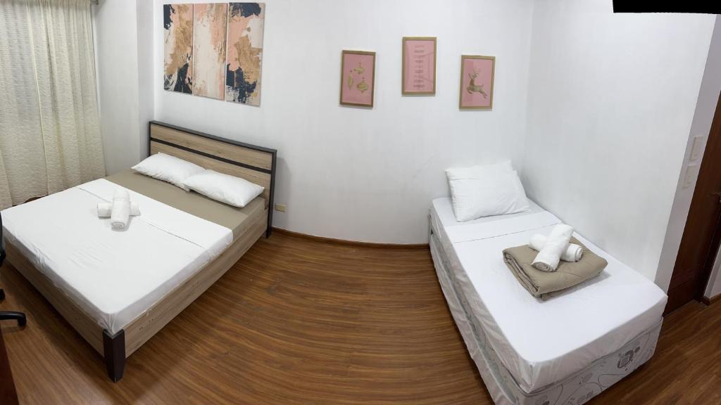 マニラにあるThe Beacon Makatiの白い壁とウッドフロアの客室で、ベッド2台が備わります。