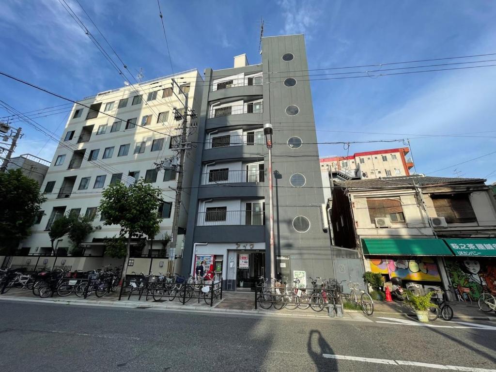 大阪市にあるHotel Aiwa for men's onlyの高い建物で、自転車が目の前に駐車されています。