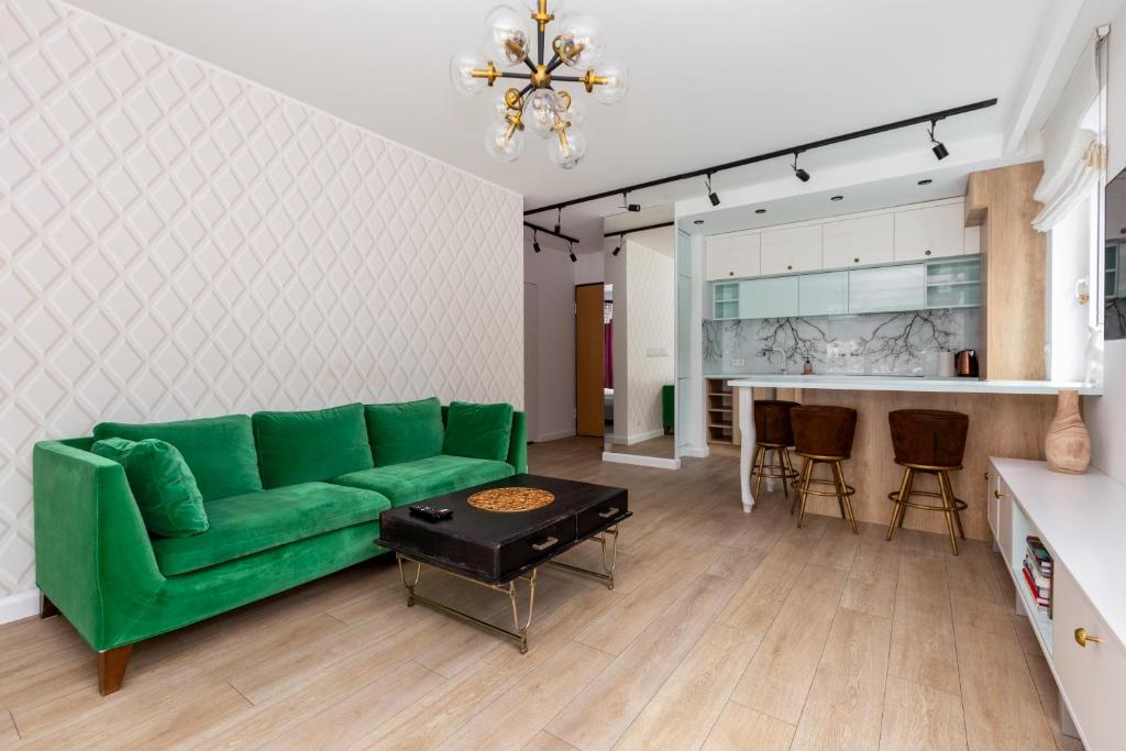 sala de estar con sofá verde y cocina en Leśna Deluxe Apartment en Gdynia