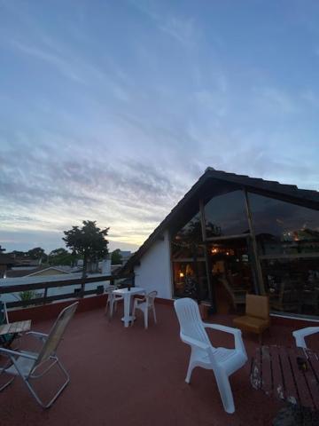 a deck with chairs and tables and a building at Las Grullas in Villa Gesell