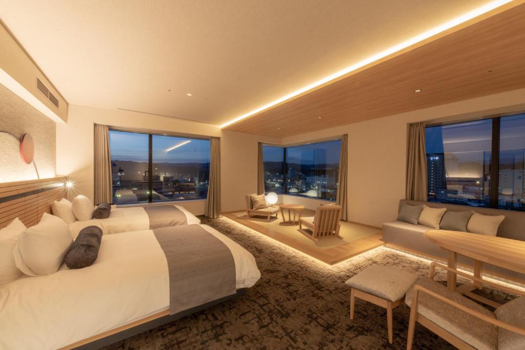 una camera d'albergo con letto, divano e finestre di Hida Takayama Onsen Takayama Green Hotel a Takayama