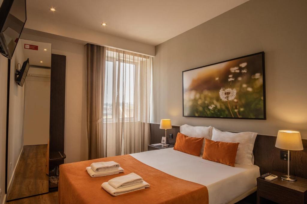 Una habitación de hotel con una cama con dos toallas. en Riversuites en Coímbra