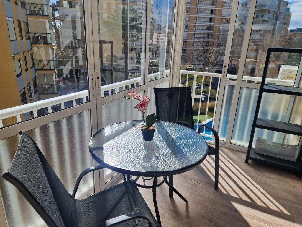a glass table with a vase of flowers on a balcony at Benidorm 2ºlinea playa in Benidorm