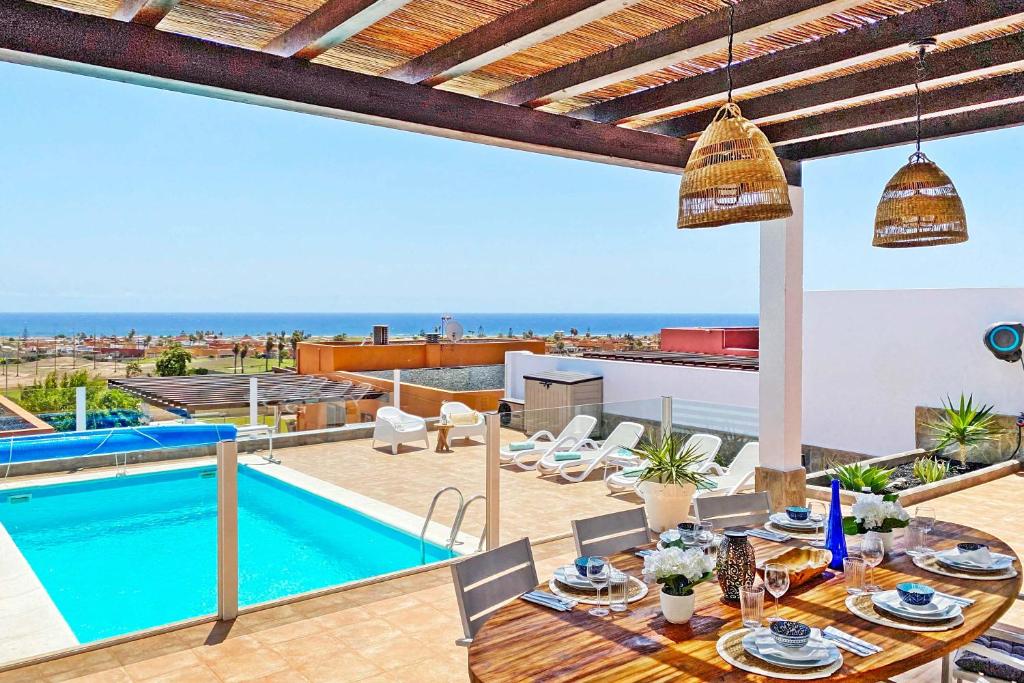 Villa con piscina y mesa de comedor. en Caleta Blanca, en La Guirra