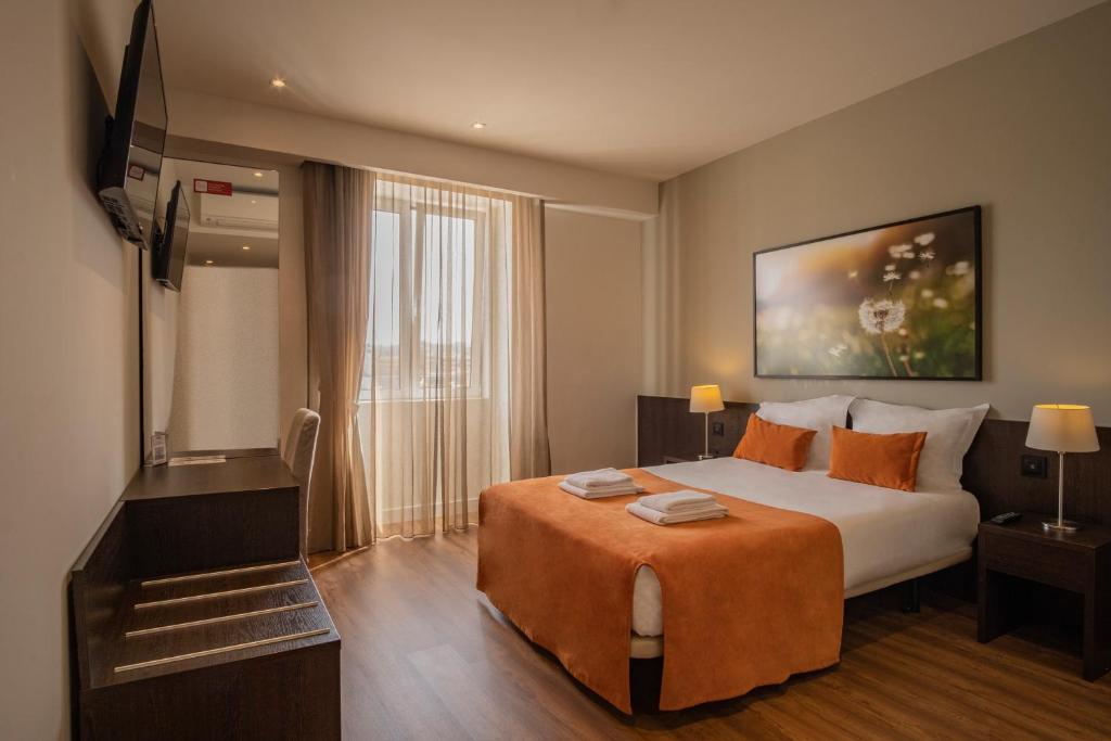 a hotel room with a bed and a flat screen tv at Riversuites in Coimbra