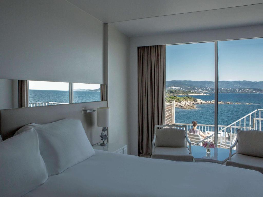 a hotel room with a bed and a view of the ocean at Sofitel Golfe d'Ajaccio Thalassa Sea & Spa in Ajaccio