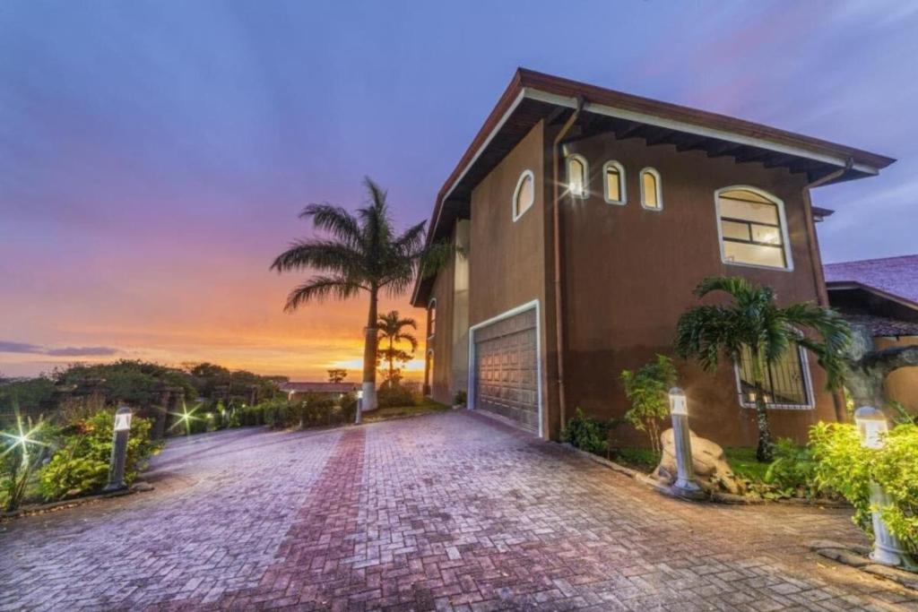 a brick driveway leading to a house at sunset at Luxury Spa Dream Villa At Lake Arenal in Tilarán