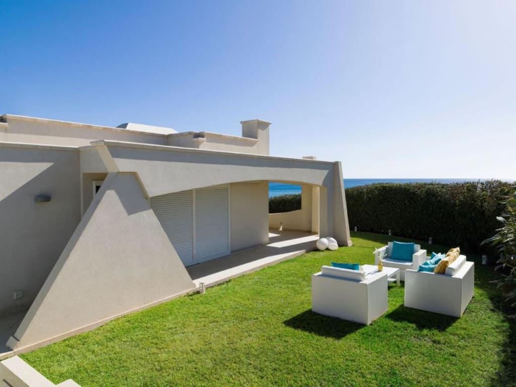 einen Hof mit zwei Stühlen und einem Haus in der Unterkunft Villa SanLorenzo Beach in Marzamemi