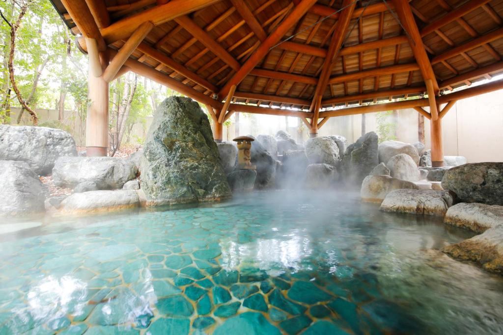 a pool of water with rocks and a waterfall at Hida Takayama Onsen Takayama Green Hotel - KEIO GROUP HOTELS - in Takayama