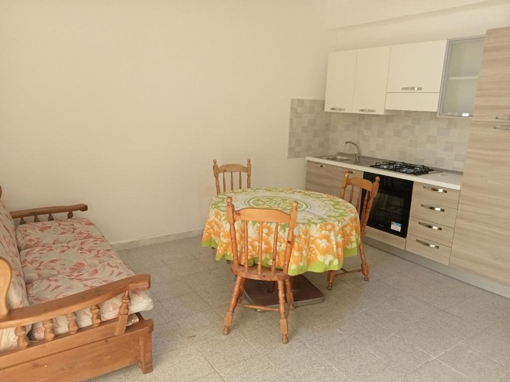 eine Küche mit einem Tisch und Stühlen sowie eine Küche mit einem Herd in der Unterkunft Casa Azzurra 56 in Bova Marina