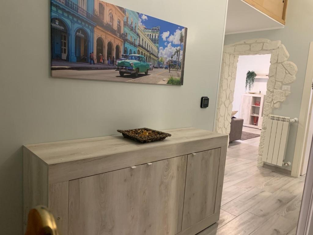 a painting hanging on a wall above a wooden cabinet at Station House in Lido di Ostia