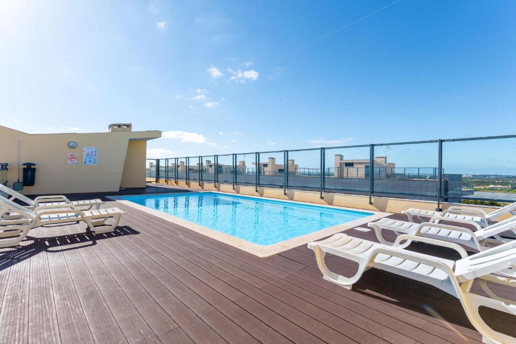 - Balcón con piscina y tumbonas en un edificio en Elegant 2 BDR Flat W/ Rooftop Pool by LovelyStay, en Olhão