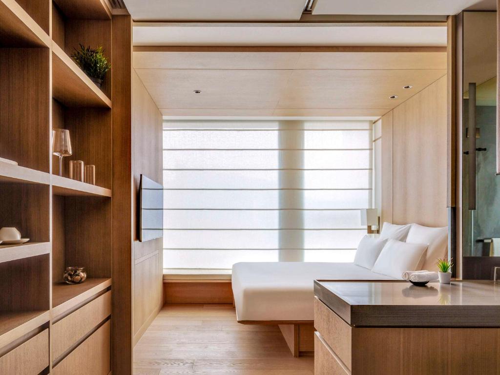 ein Schlafzimmer mit einem Bett und einem großen Fenster in der Unterkunft AKI Hong Kong - MGallery in Hongkong