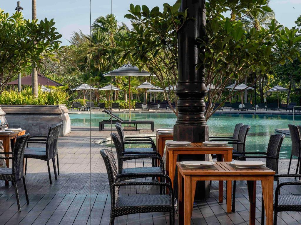 a group of tables and chairs next to a pool at Pullman Phuket Karon Beach Resort in Karon Beach