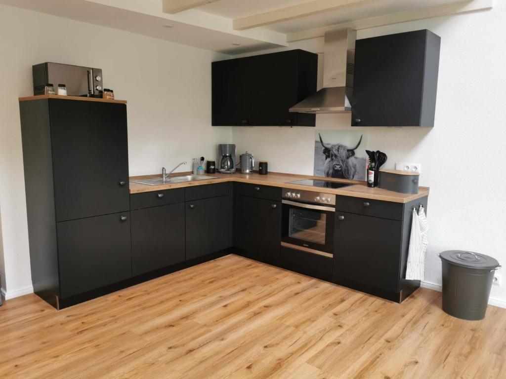 cocina con electrodomésticos negros y suelo de madera en Ferienwohnung Seeloft, en Emden
