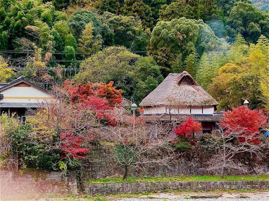 uma casa com telhado de palha numa floresta em 洋々庵・古民家一棟貸・完全貸切・プライベートサウナ em Furuyu