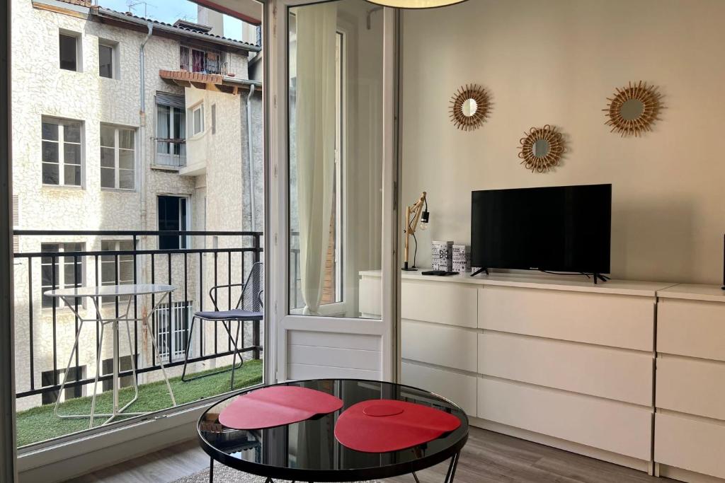uma sala de estar com uma mesa, uma televisão e uma varanda em Le Saint François Hypercentre #AR em Grenoble