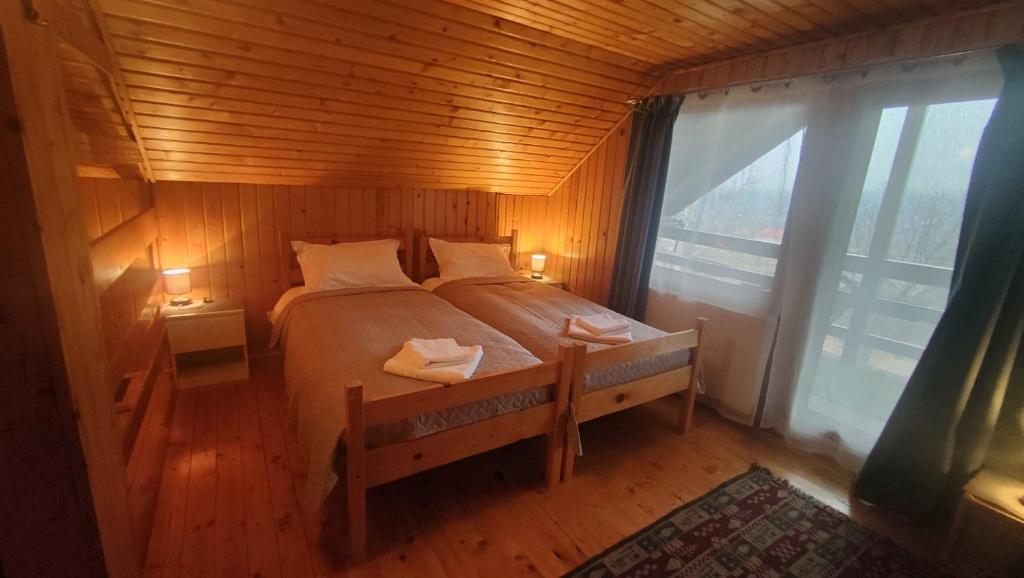 ein Schlafzimmer mit einem Bett und einem großen Fenster in der Unterkunft Casa Ciubărului Bran in Predeluţ