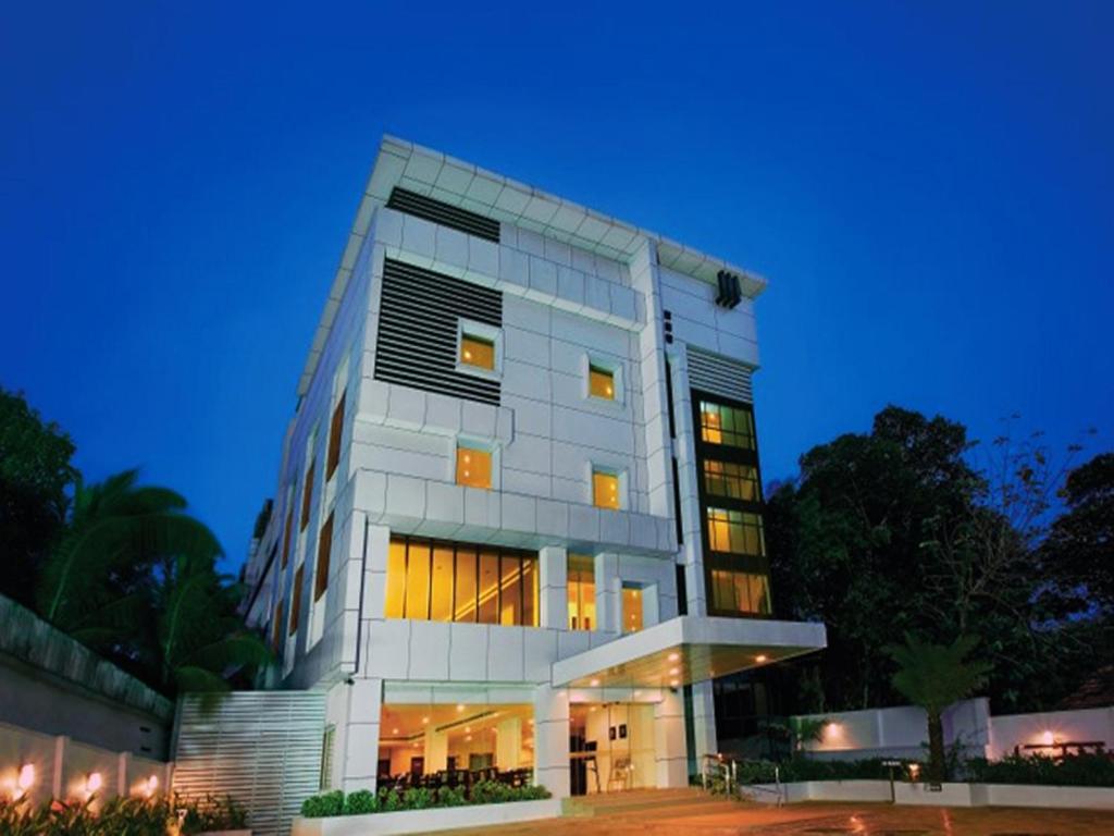 a tall white building with many windows at night at Hotel Hills Park in Pathanāmthitta