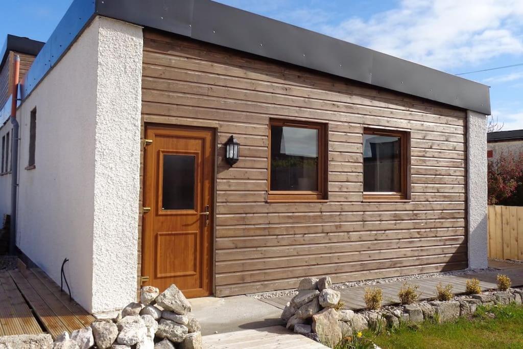 a small house with a wooden door and windows at Holiday House with garden and sauna in Durness