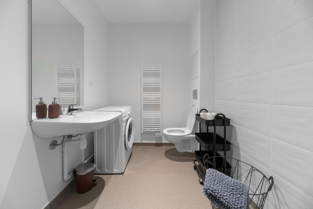 a white bathroom with a sink and a toilet at Résidence Léon Blum - Appartements design - Parking in Clermont-Ferrand