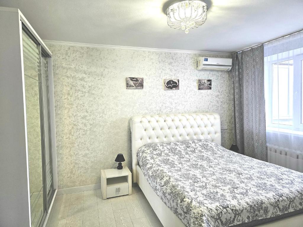 a bedroom with a white bed and a chandelier at Apartment in City Center, street Banulescu Bodoni 57 in Chişinău