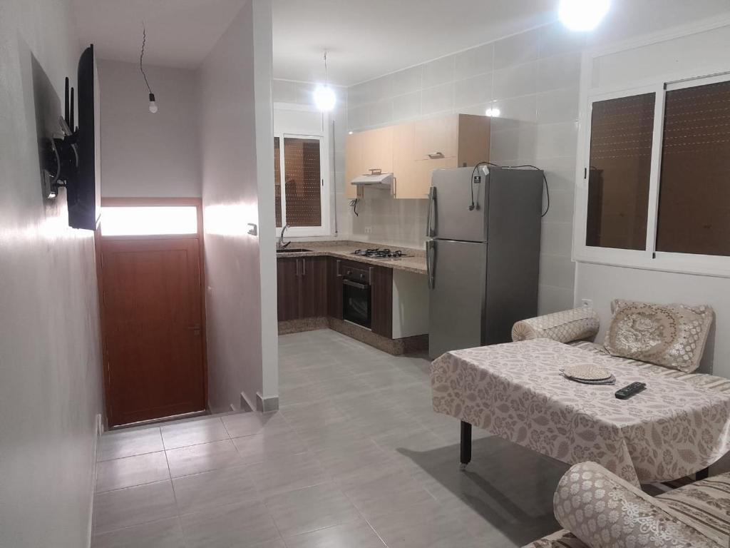 a kitchen and a living room with a table and a refrigerator at Alhoceima Ville Appartement in Al Hoceïma