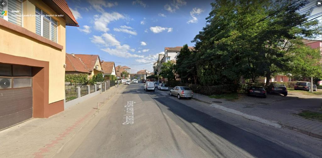 una calle vacía con coches aparcados en la carretera en Sophia's Cozy Apartment, en Mediaş