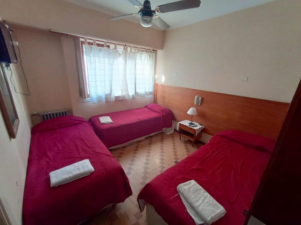 two beds in a room with red sheets at Nuevo Hotel Tivoli in Mar del Plata